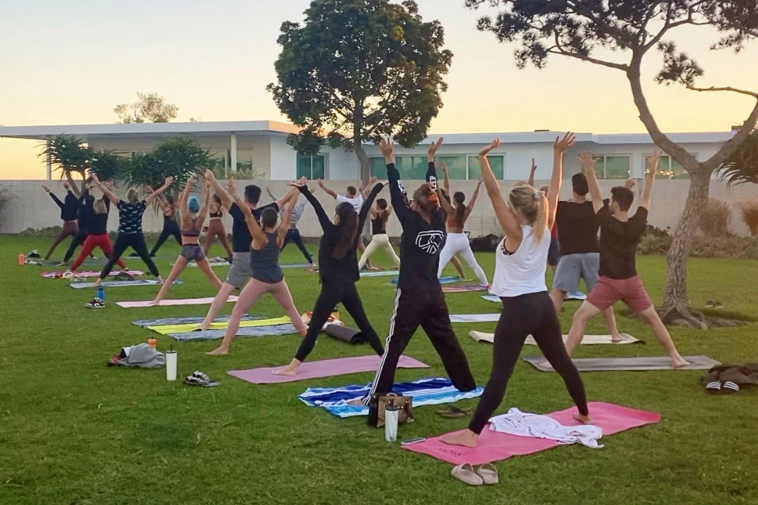 group of yogis performing starpose during a yoga class in the park