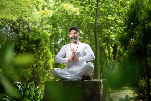 Indian man doing yoga meditation in forest