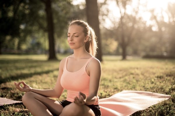 Female meditating while sitting in a mat