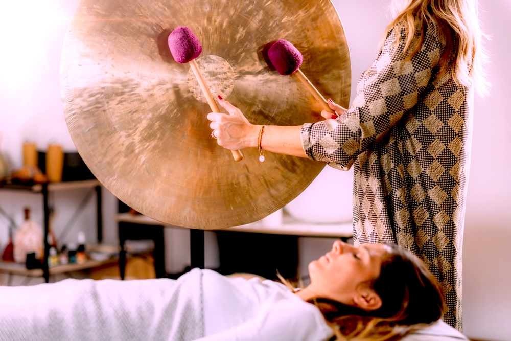 A woman lies down with her eyes closed during a sound bath session