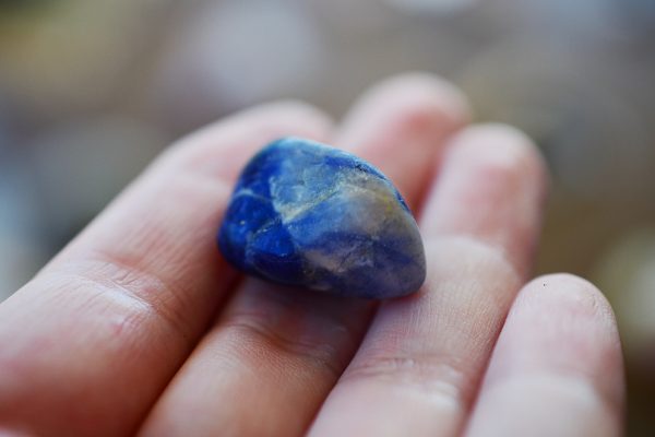 Throat chakra crystal sodalite on the palm of a hand