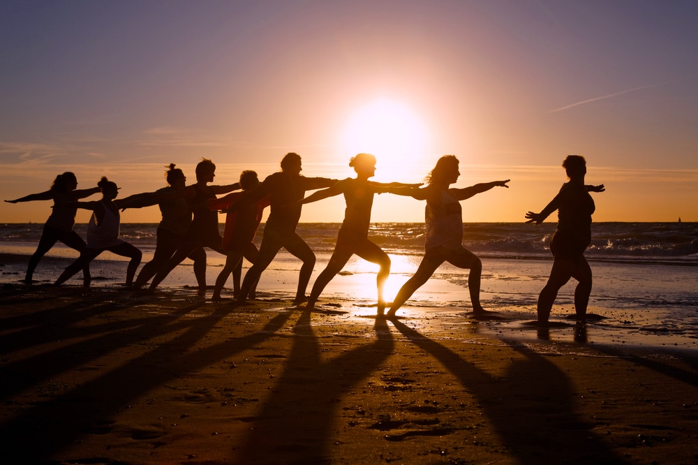 Group yoga class at the beach during sunset