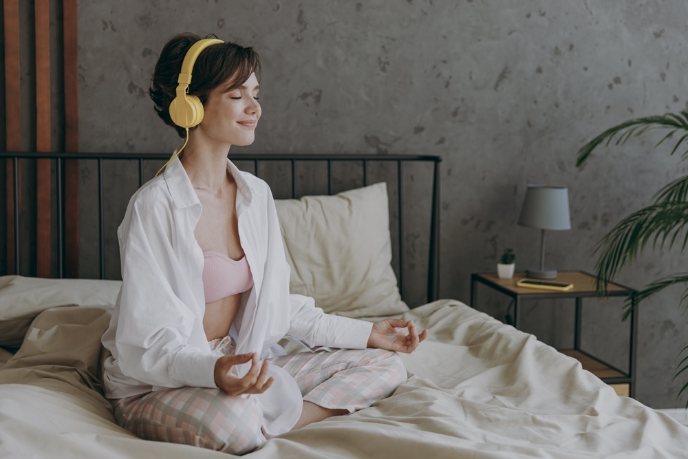 Woman in bed listening to affirmations on her headset