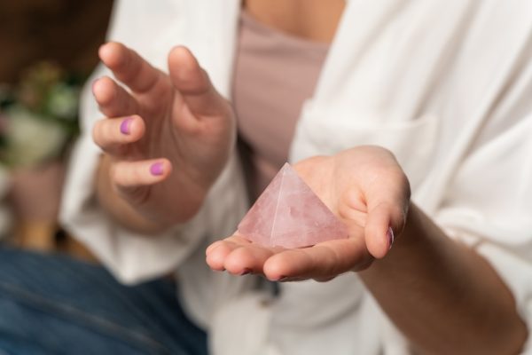 Woman holding a large rose quartz crystal on her hand