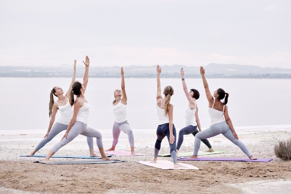 Female yoga enthusiasts doing yoga on the beach