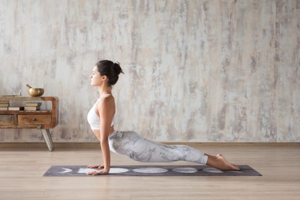 Female yogi practicing yoga indoors on a mat