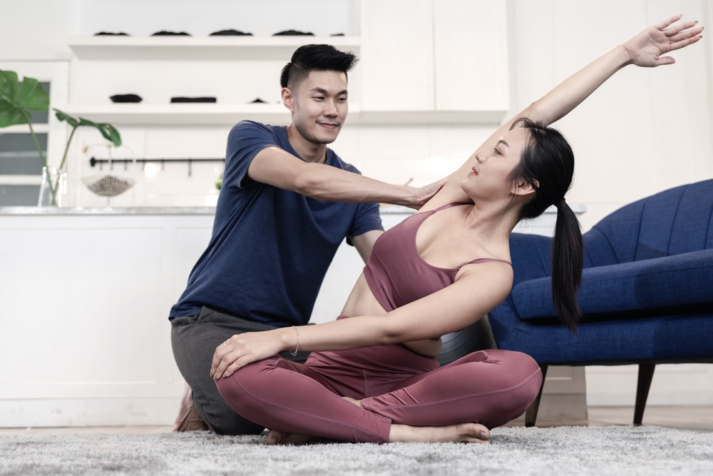 Male yoga instructor teaching a female student during a private yoga class