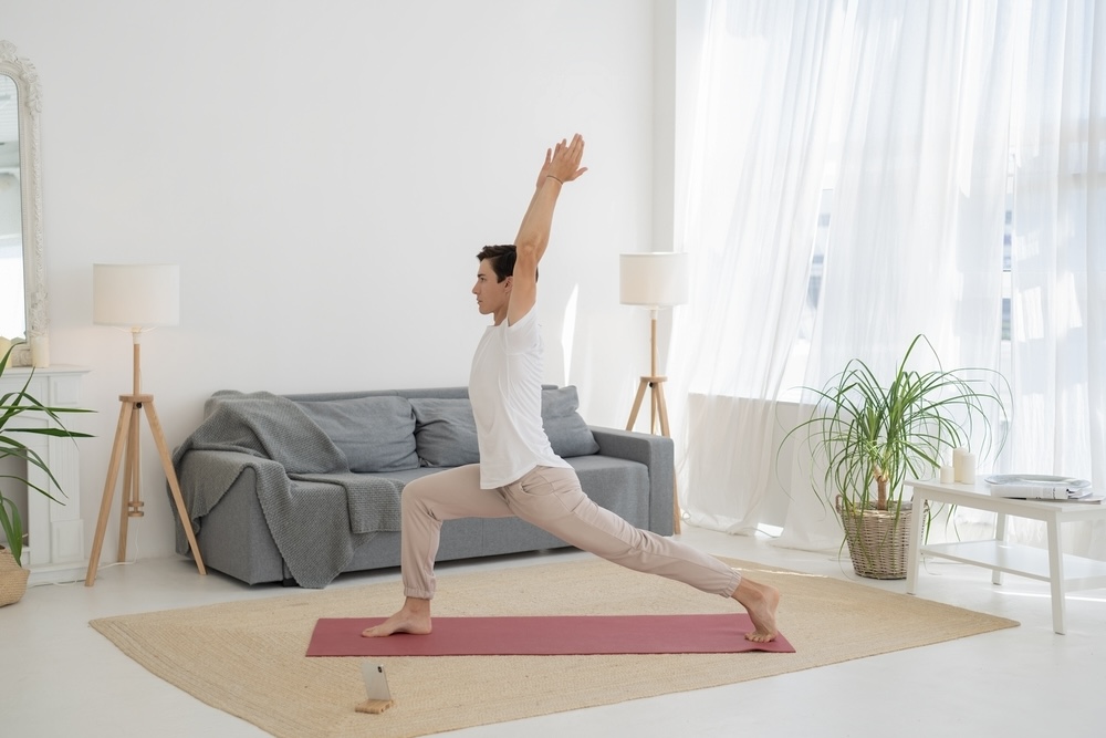 Man practicing Vinyasa yoga inside his living room