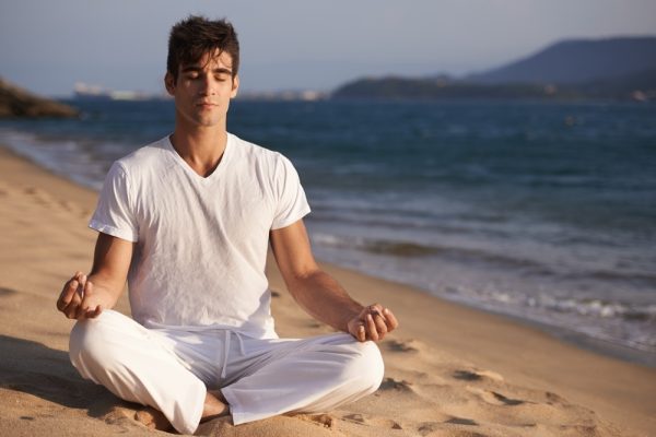 Man meditating on the beach with crown chakra affirmations