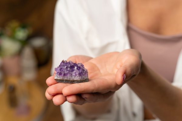 Woman’s hand holding an amethyst stone