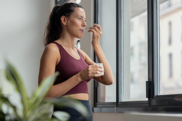 Young fitness enthusiast eating yogurt before exercise