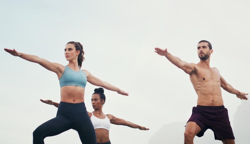 Group of young adults doing beginner yoga outdoors