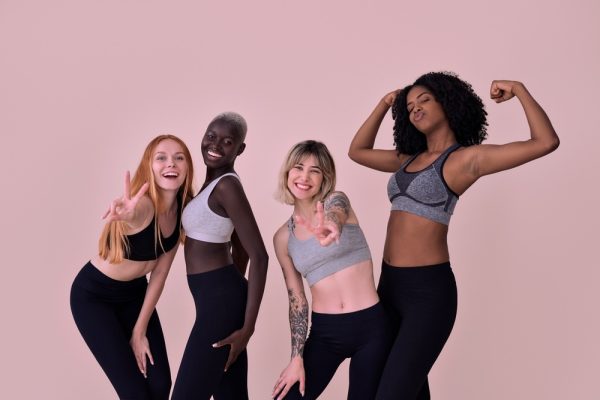 Good-looking females smiling to the camera after a beginner yoga class in OC