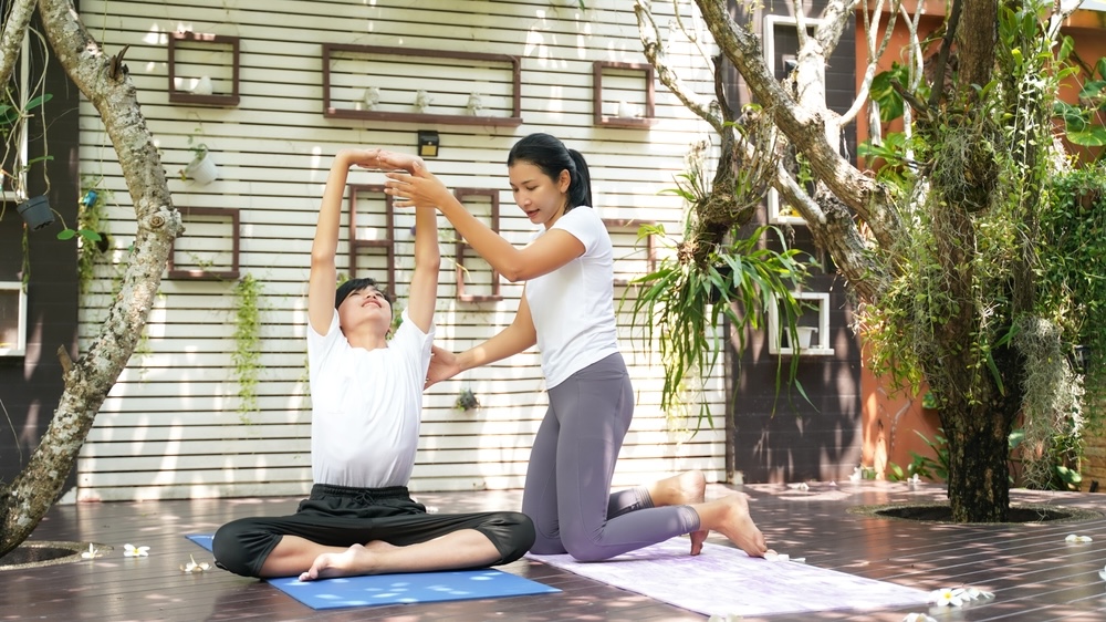 Yoga teacher with a student outdoors