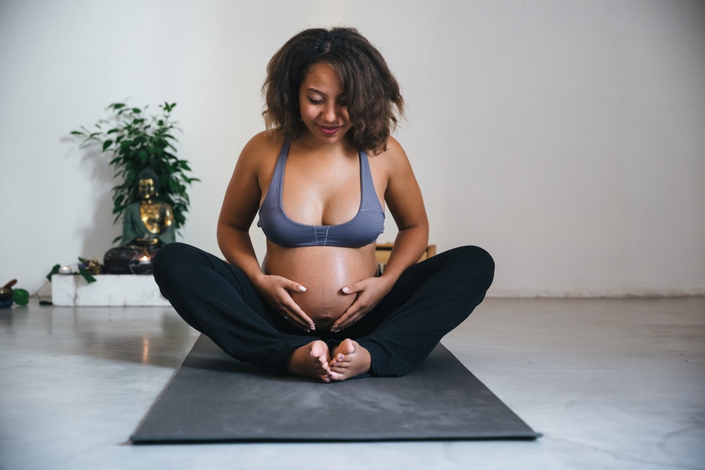 Woman sitting on a mat waiting for prenatal yoga class to begin