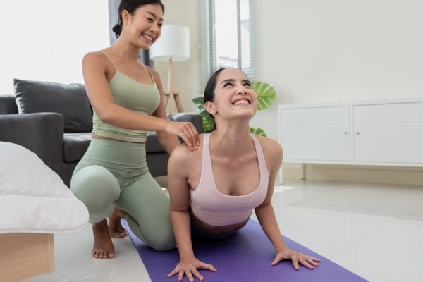 Female yoga instructor guiding a student in the living room